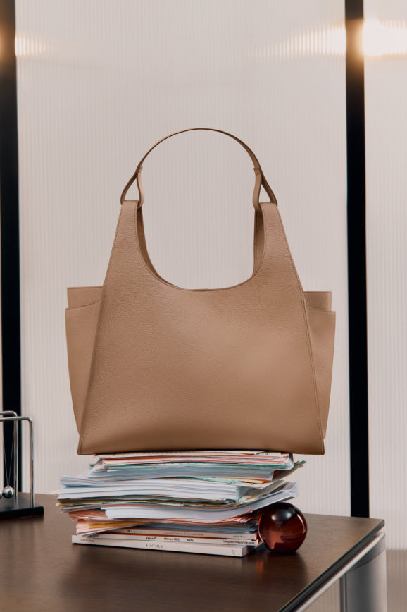 Handbag on a stack of papers on an office desk.