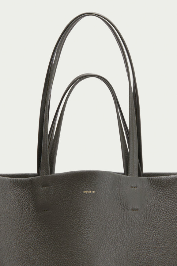 Close-up of a handbag with two handles and a logo on front.