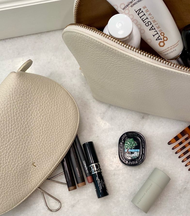 Cosmetic products arranged around an open makeup bag.