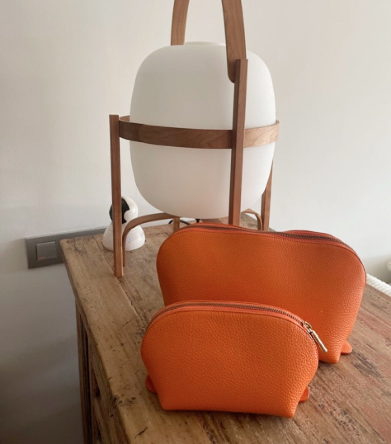 Two purses on a table with a chair in the background.