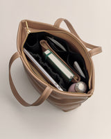 Open travel bag with books, laptop, umbrella, and water bottle inside.