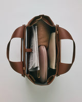 Open travel bag with contents including a newspaper, and various neatly arranged items.