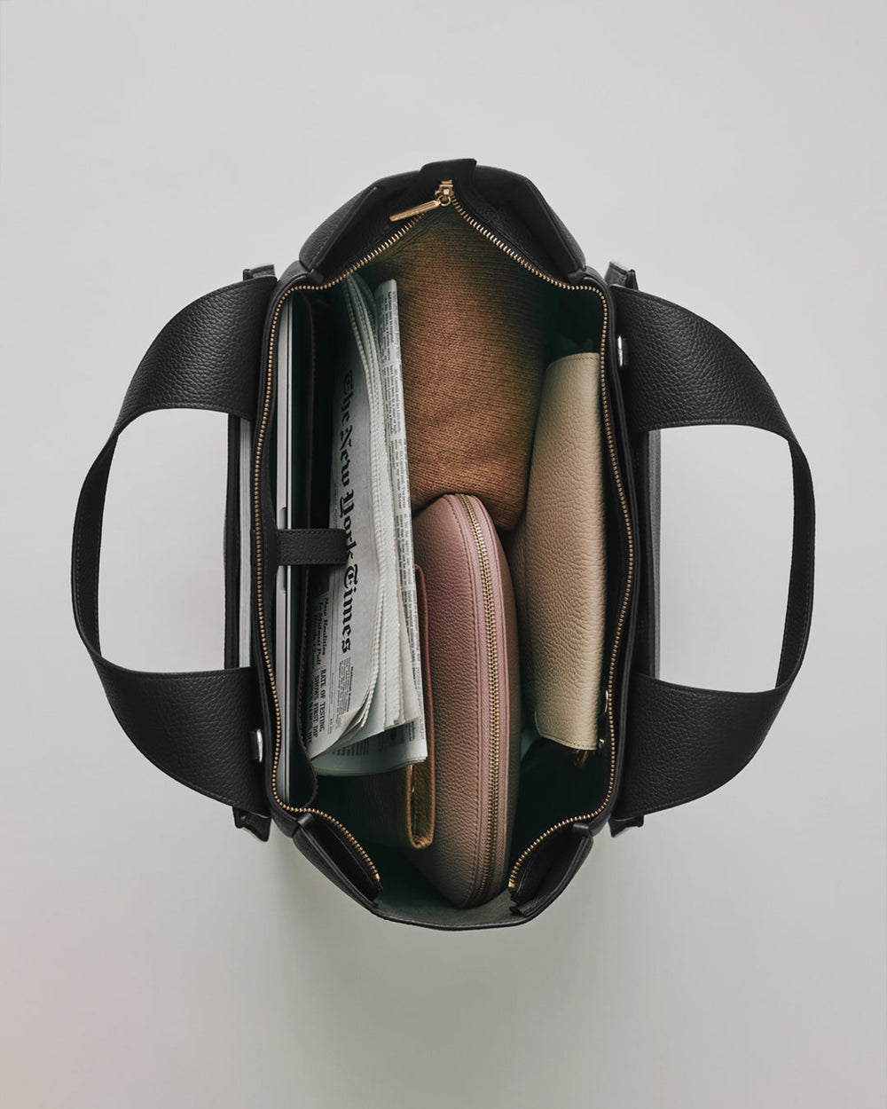 Mila Satchel Open travel bag with a newspaper, a laptop, and two pouches inside