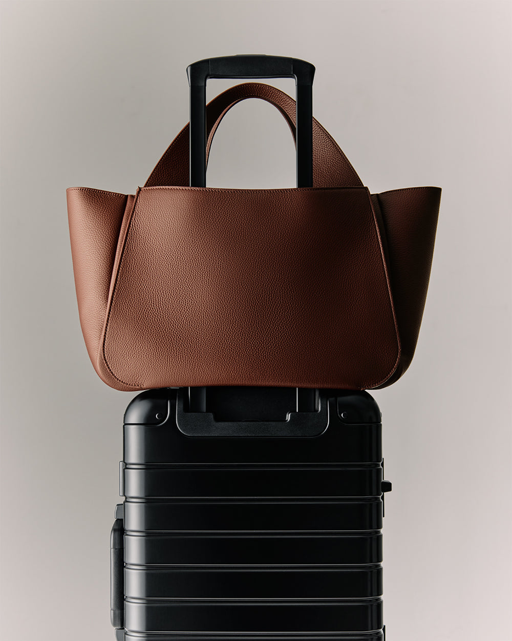 Mila Satchel Handbag placed on top of a rolling suitcase