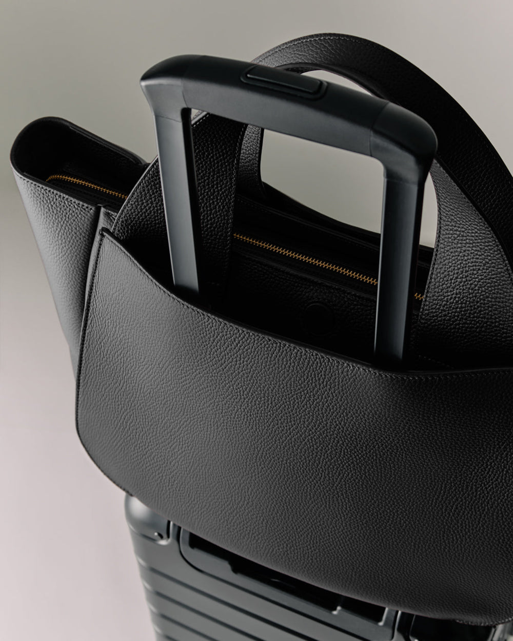 Mila Satchel Large handbag attached to the retractable handle of a suitcase.