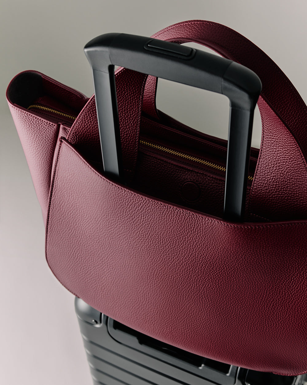 Mila Satchel Large handbag attached to the retractable handle of a suitcase.