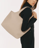 Woman holding a large handbag over her shoulder.