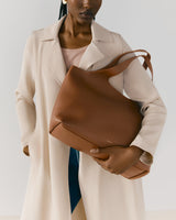 Person holding a large tote bag wearing a coat.