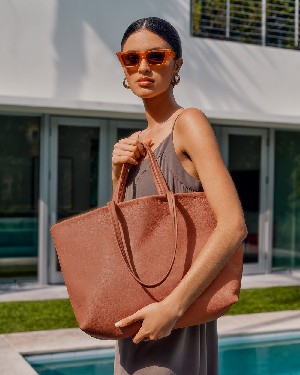Classic Easy Tote Woman in a dress holding a large tote bag by a poolside.