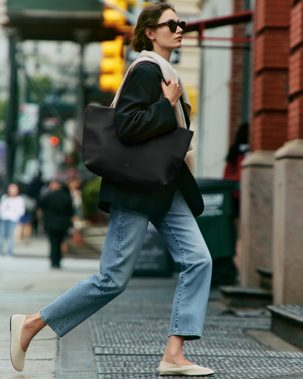 Person walking on city street carrying large tote bag over shoulder