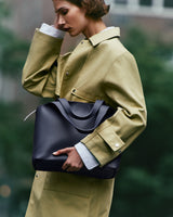 Person holding a bag and wearing a coat outside