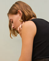 Person wearing hoop earrings and a sleeveless top, looking down.