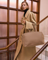 Person on stairs holding a travel bag and wearing a long coat