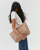 Person holding a large handbag wearing a white shirt and jeans