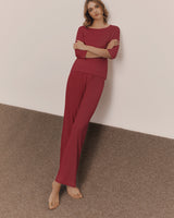 Person in relaxed clothing leaning against a wall with arms crossed.