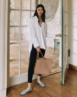 Woman with a tote bag standing by a glass door.