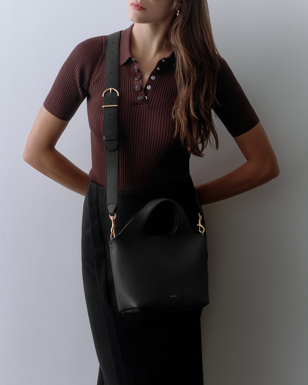 Person wearing a short-sleeve shirt and skirt with a shoulder bag.