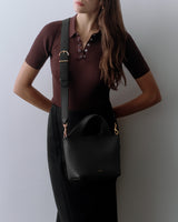 Person wearing a short-sleeve shirt and skirt with a shoulder bag.