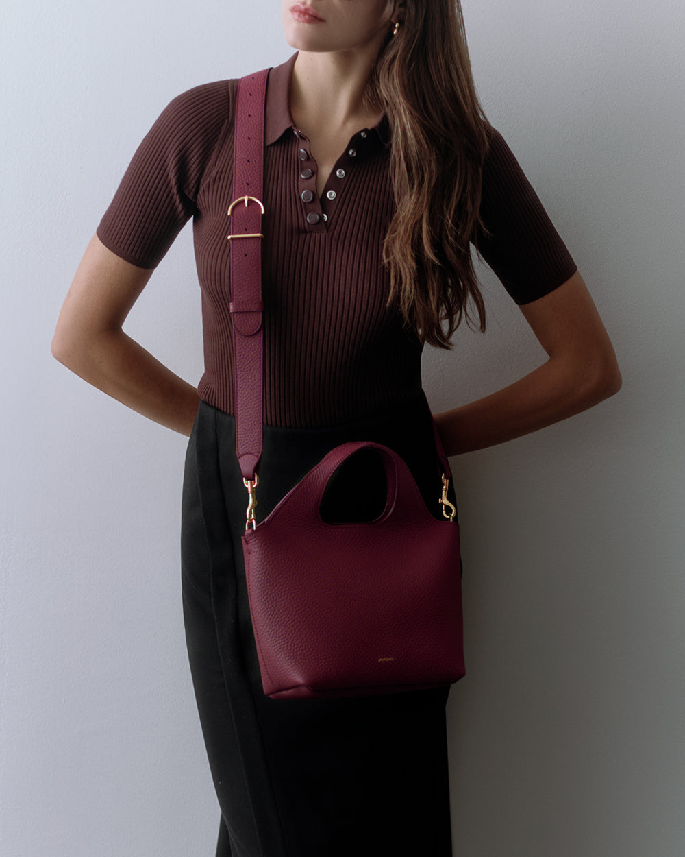 Mini System Tote Person wearing a short-sleeve shirt and skirt with a shoulder bag.