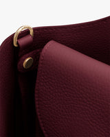 Close-up of a bag with a flap and gold hardware.