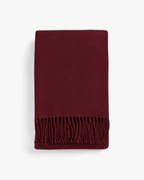Folded fringed scarf on a plain background.