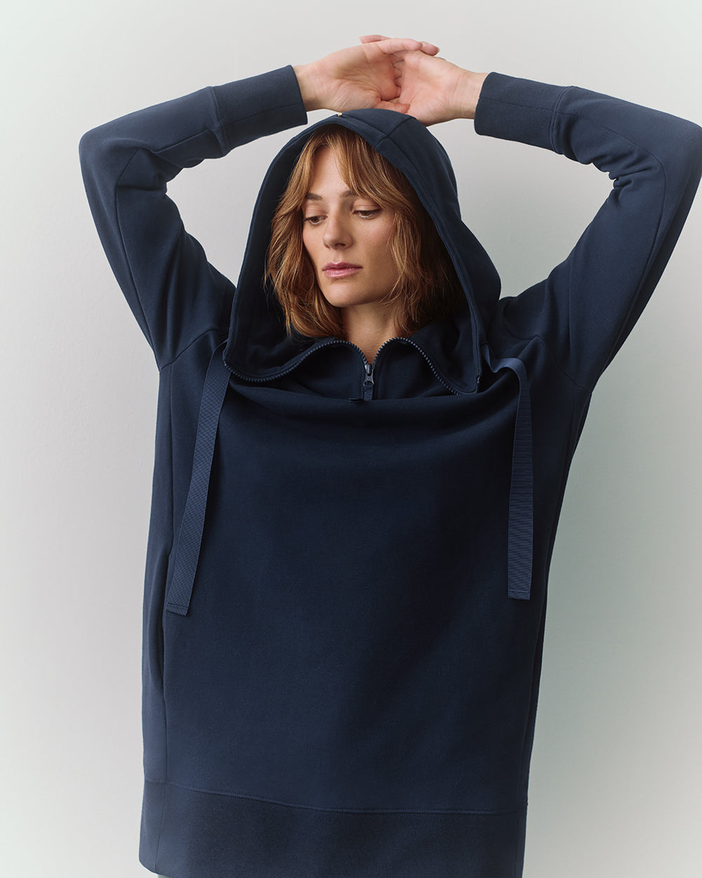 Person wearing a hoodie with arms raised above the head
