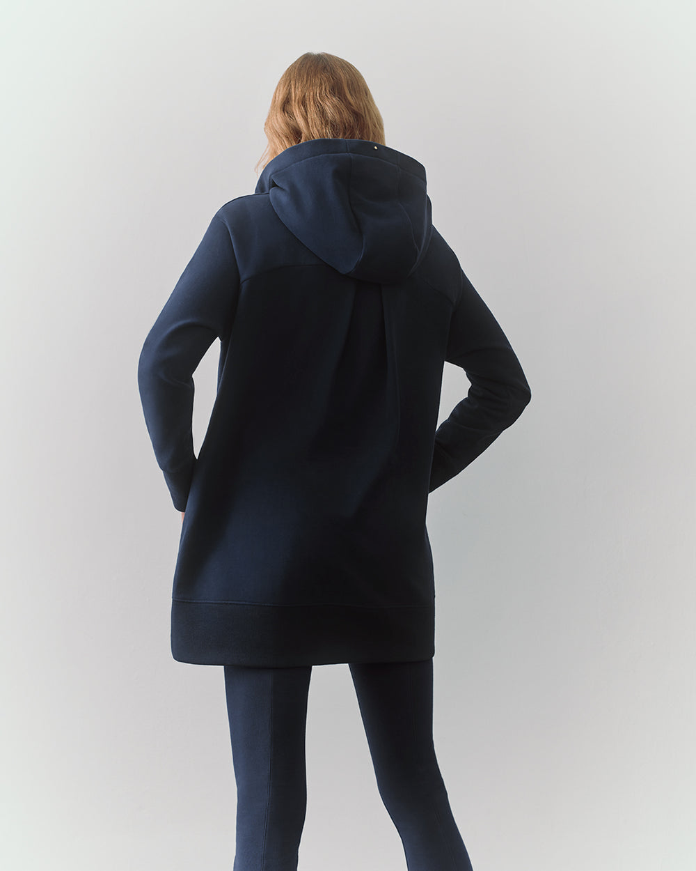 Person facing away wearing a long hoodie and pants.