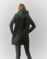 Person wearing hooded sweater and pants, facing away.