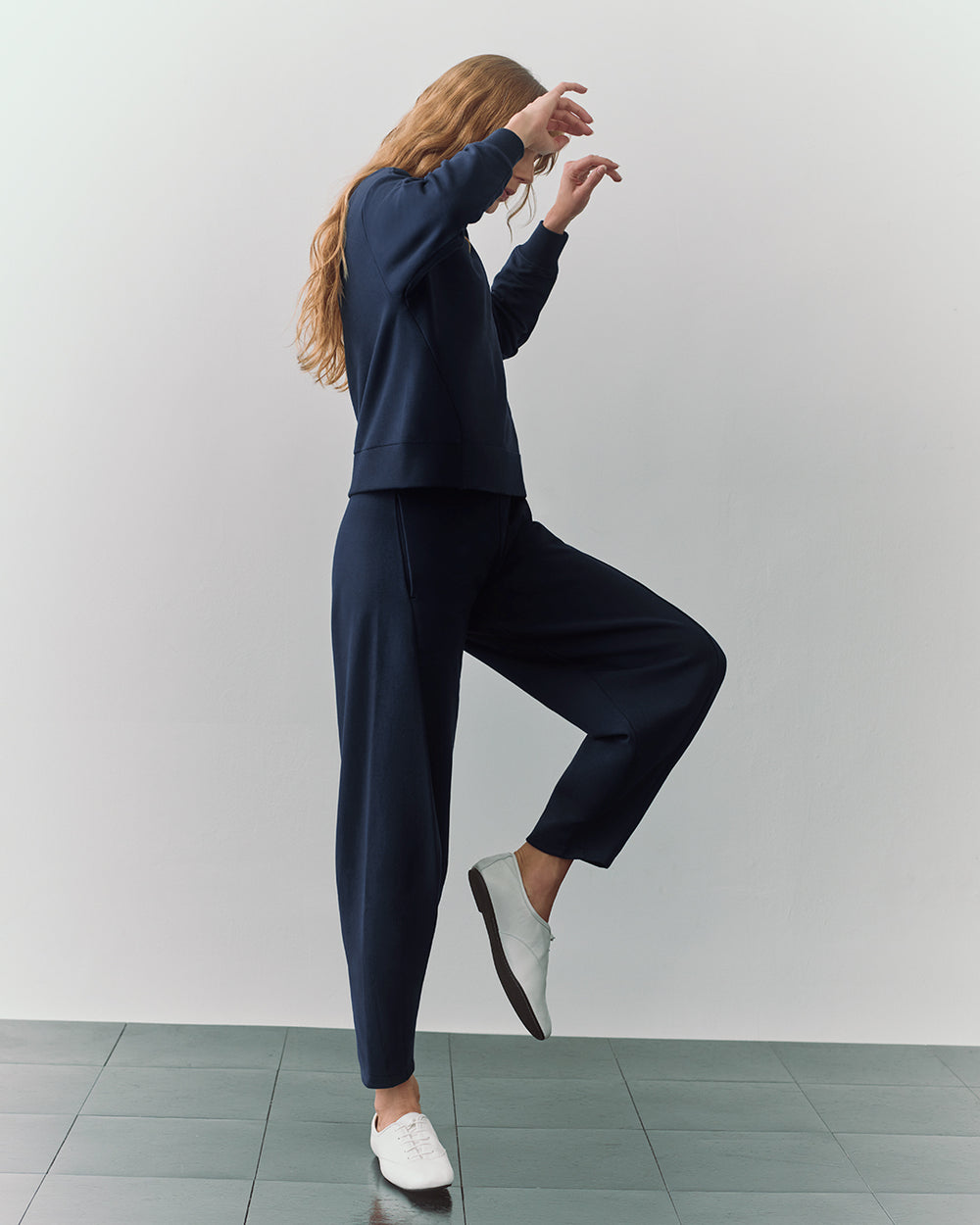 Fleece Cropped Sweatshirt Person in a two-piece outfit, standing on one leg with arms raised.