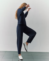 Person in a two-piece outfit, standing on one leg with arms raised.