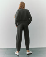 Person in a matching sweatshirt and pants set, standing on a tile floor, facing away.