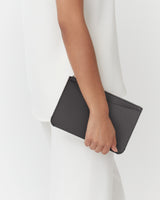Person holding a textured clutch against their side.