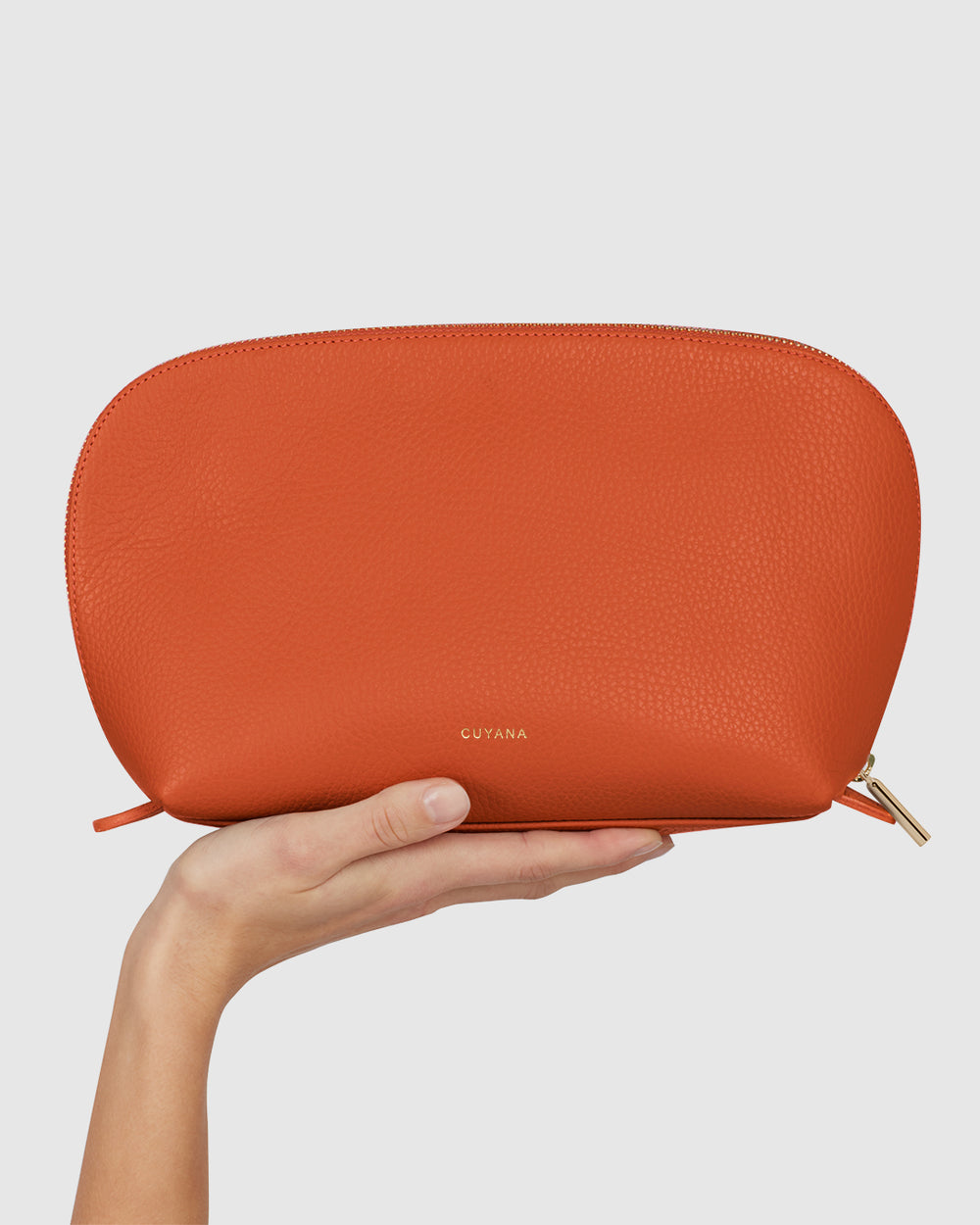 Travel Case Set Hand holding a semi-circular pouch with a zipper.