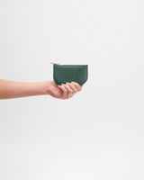 Hand holding a small zippered pouch against a plain background