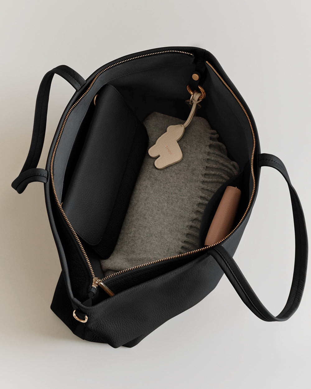 Open tote bag with a folded sweater, pouch, and a small keychain inside.