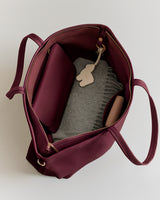 Open tote bag with a folded sweater, pouch, and a small keychain inside.