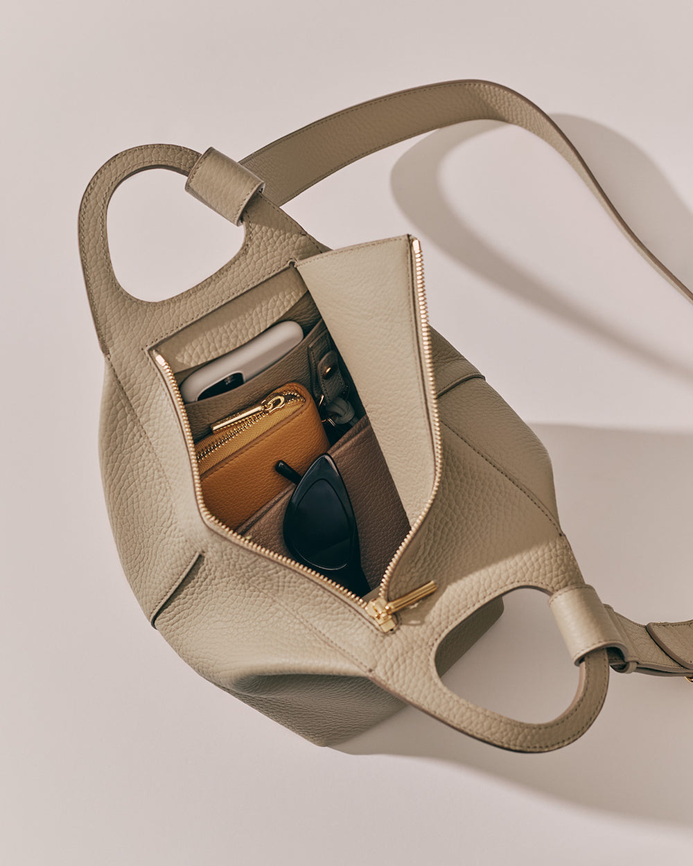 Paloma Bag Open handbag with a wallet, sunglasses, and other items inside