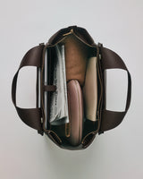 Open top view of a tote bag with accessories and a newspaper inside