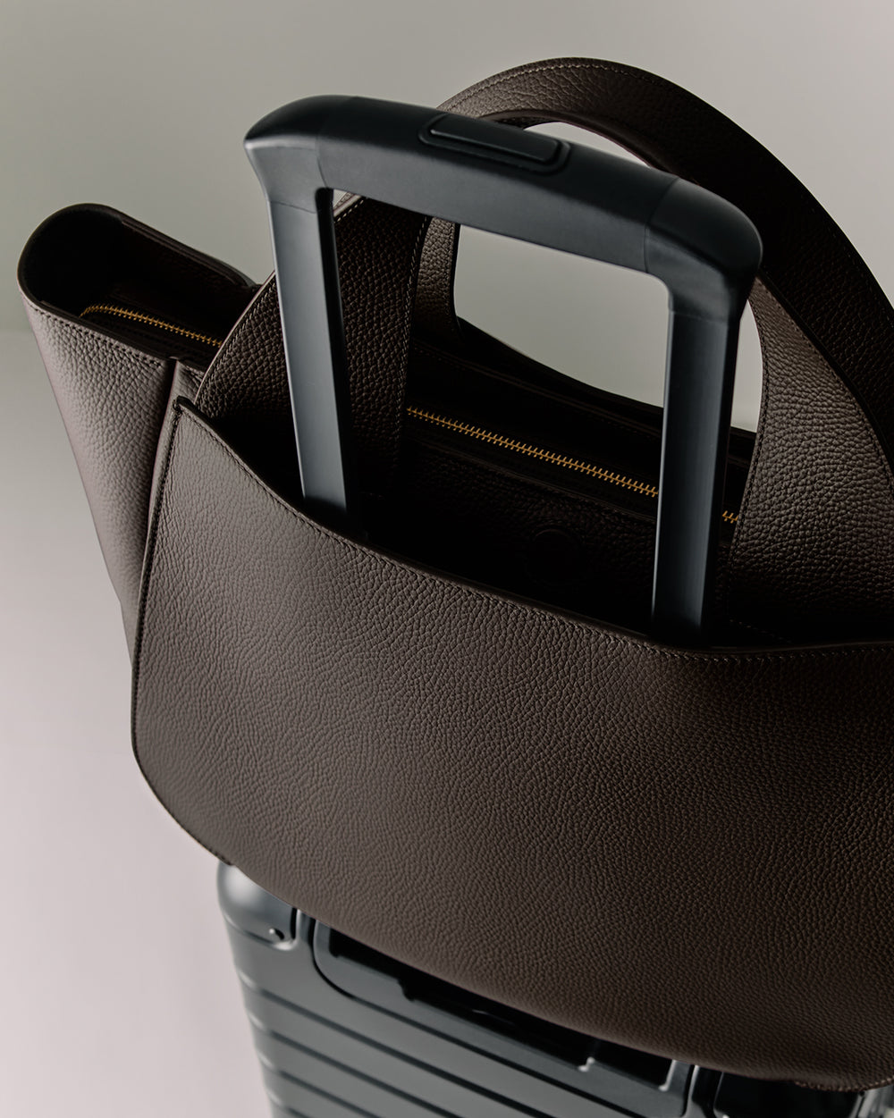 Mila Satchel Luggage handle with a bag looped over it