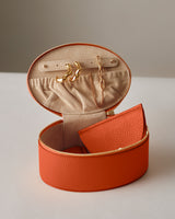 Open jewelry case with earrings, chain, and leather pouch inside.