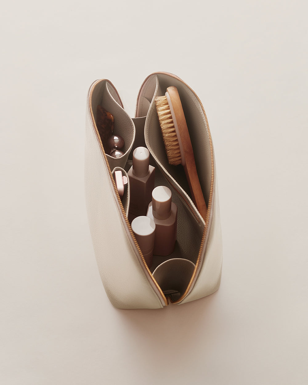 Voyager Travel Case Open zippered pouch with bottles and a brush inside