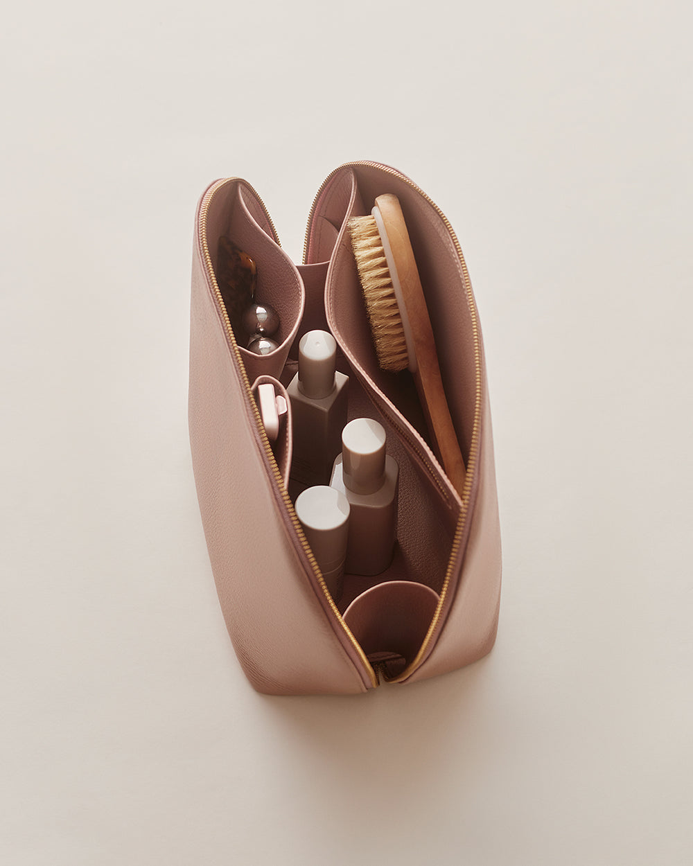 Voyager Travel Case Open zippered pouch with bottles and a brush inside