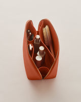 Open toiletry bag with bottles, brush, and grooming items inside.