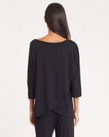 Woman viewed from behind wearing a loose top and pants.