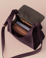 Open handbag with two zippered pouches and a book inside.