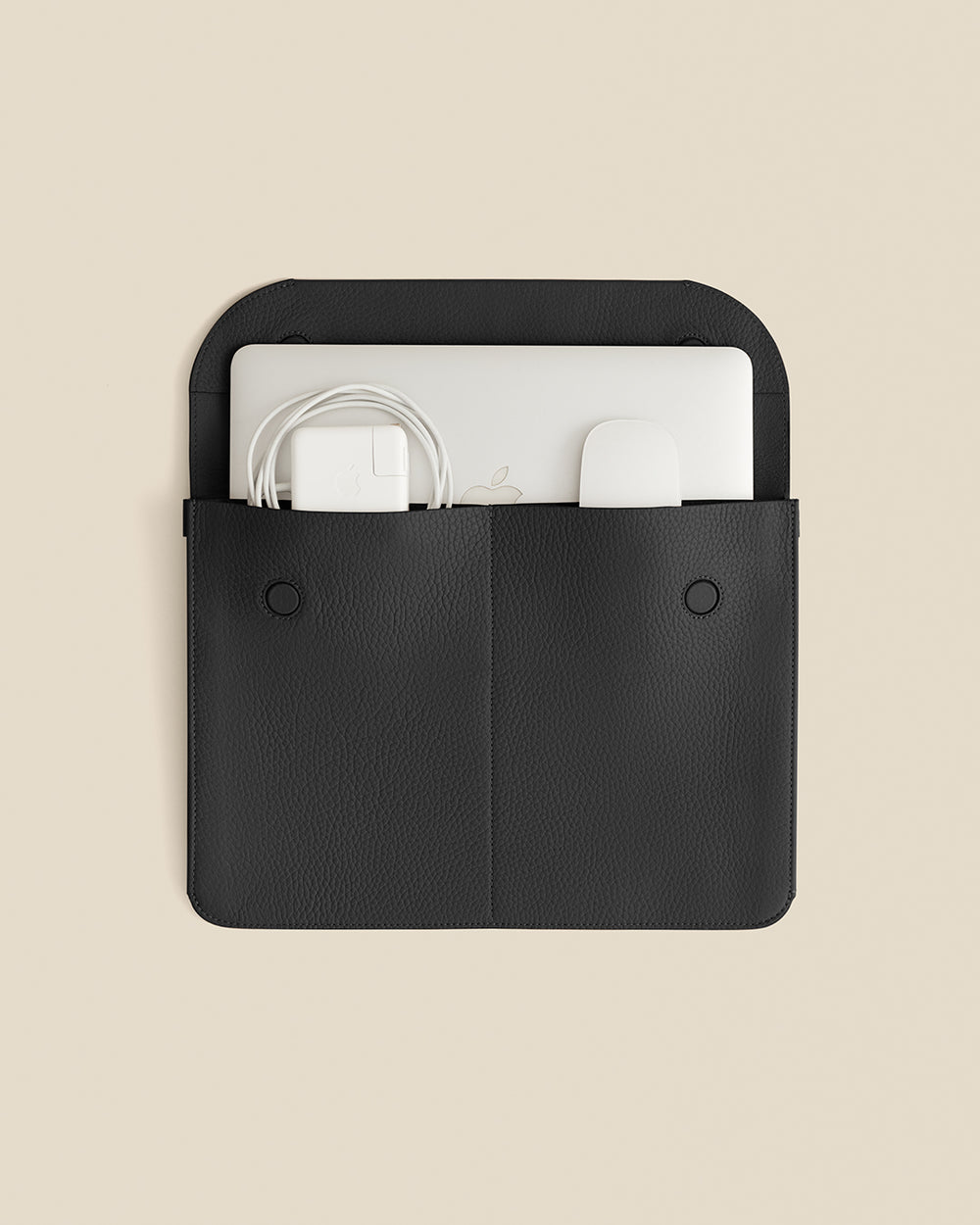 Laptop sleeve with two pockets holding a laptop and cables
