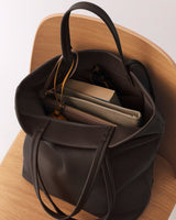 Open tote bag on chair with books and a pouch inside.