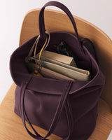 Open tote bag with books and accessories inside on a chair