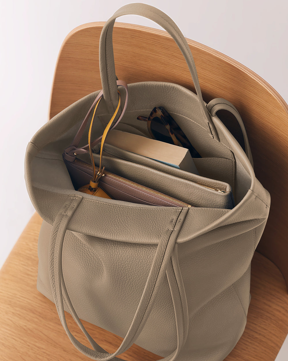 Tall Easy Tote Open tote bag on a chair with books, wallet, and sunglasses inside.