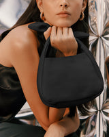 Person holding a handbag with shiny background.